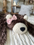 Close-up front view focusing on the right side of the brown faux fur bear rug face. Shows the plush fabric texture and cream crochet muzzle and ear details on a cream carpet. Cozy woodland nursery decor.