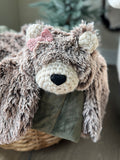 A plush bear lovey made with brown and beige tipped faux fur and a pink crochet bow by its ear.